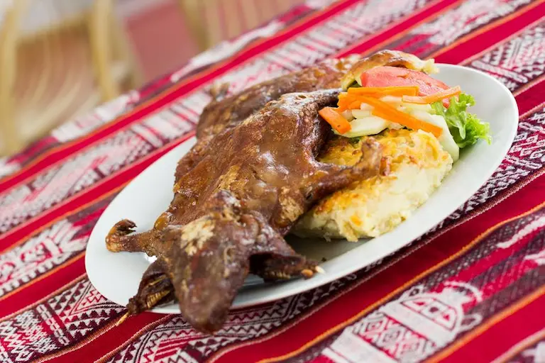 Plato típico peruano Chiriuchu, compuesto por carne, maíz y verduras en un plato colorido.