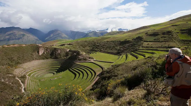 Paisaje del Valle Sagrado de los Incas mostrando verdes campos y montañas al fondo.