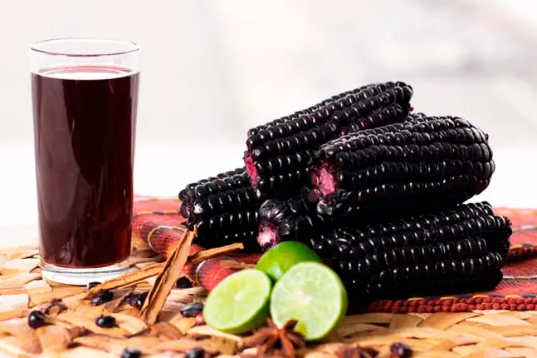 Vaso de chicha morada acompañado de limón, canela y maíz morado.