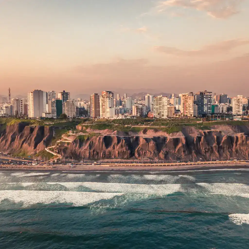 Vista panorámica de la Costa Verde en Lima con edificios modernos sobre acantilados frente al mar.
